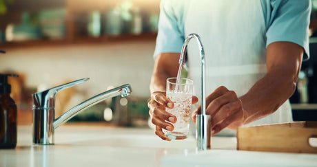 Reverse osmosis faucet dispensing clean water into a glass in a kitchen setting