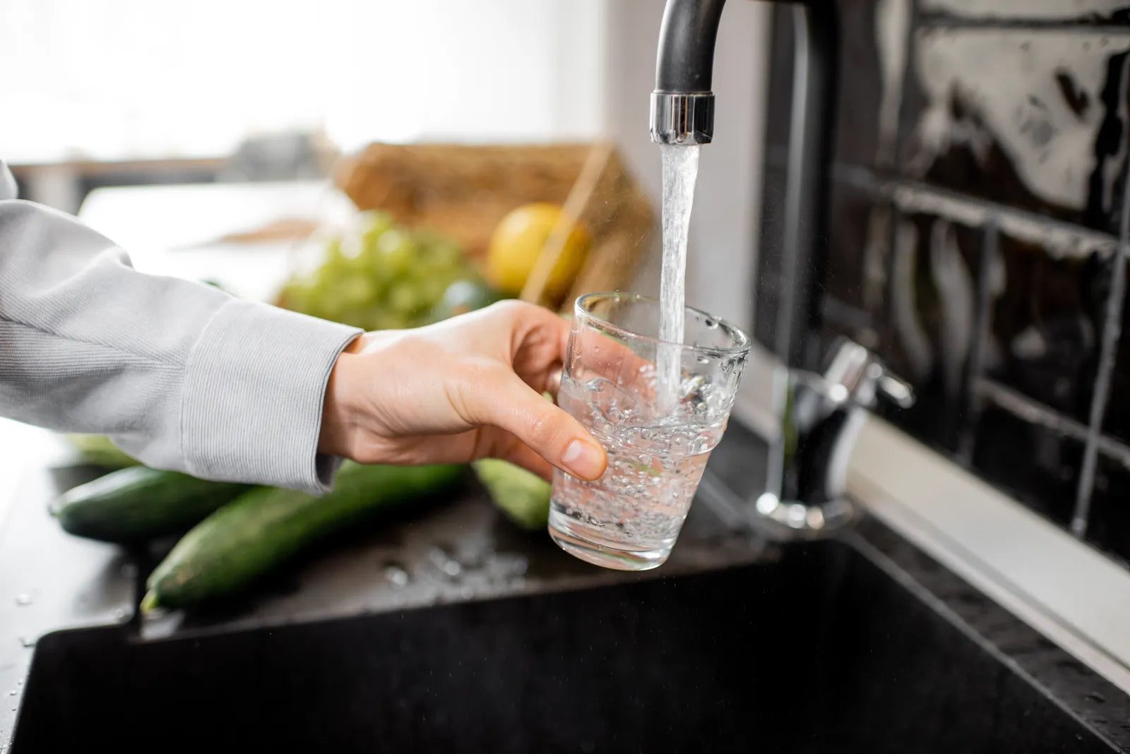Daily life shot: Hand pouring water into a glass, alongside our guide to fluoride removal filters