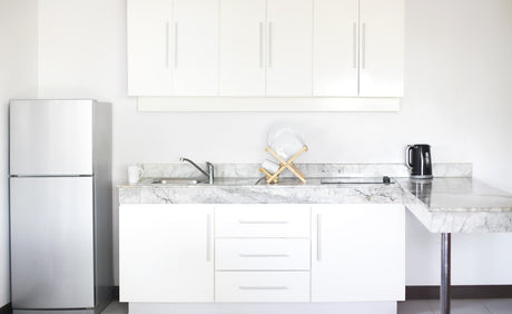 Bright kitchen with a refrigerator, sink, countertop, and cabinets for a water filter setup.