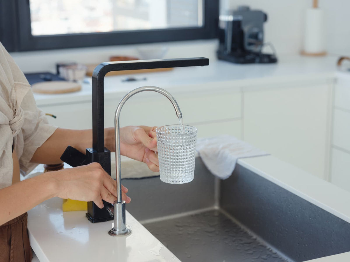 Glass of drinking water beside a residential kitchen sink in a bright Florida-style home.