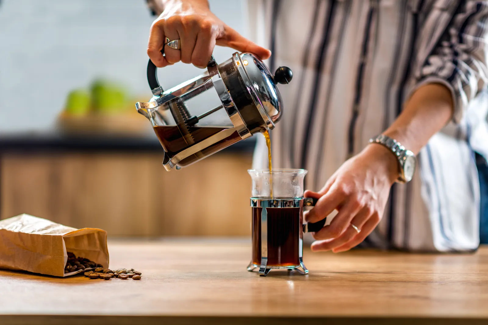 Pouring freshly brewed coffee from a French press into a cup, showcasing the rich flavor and aroma enabled by quality filtered water