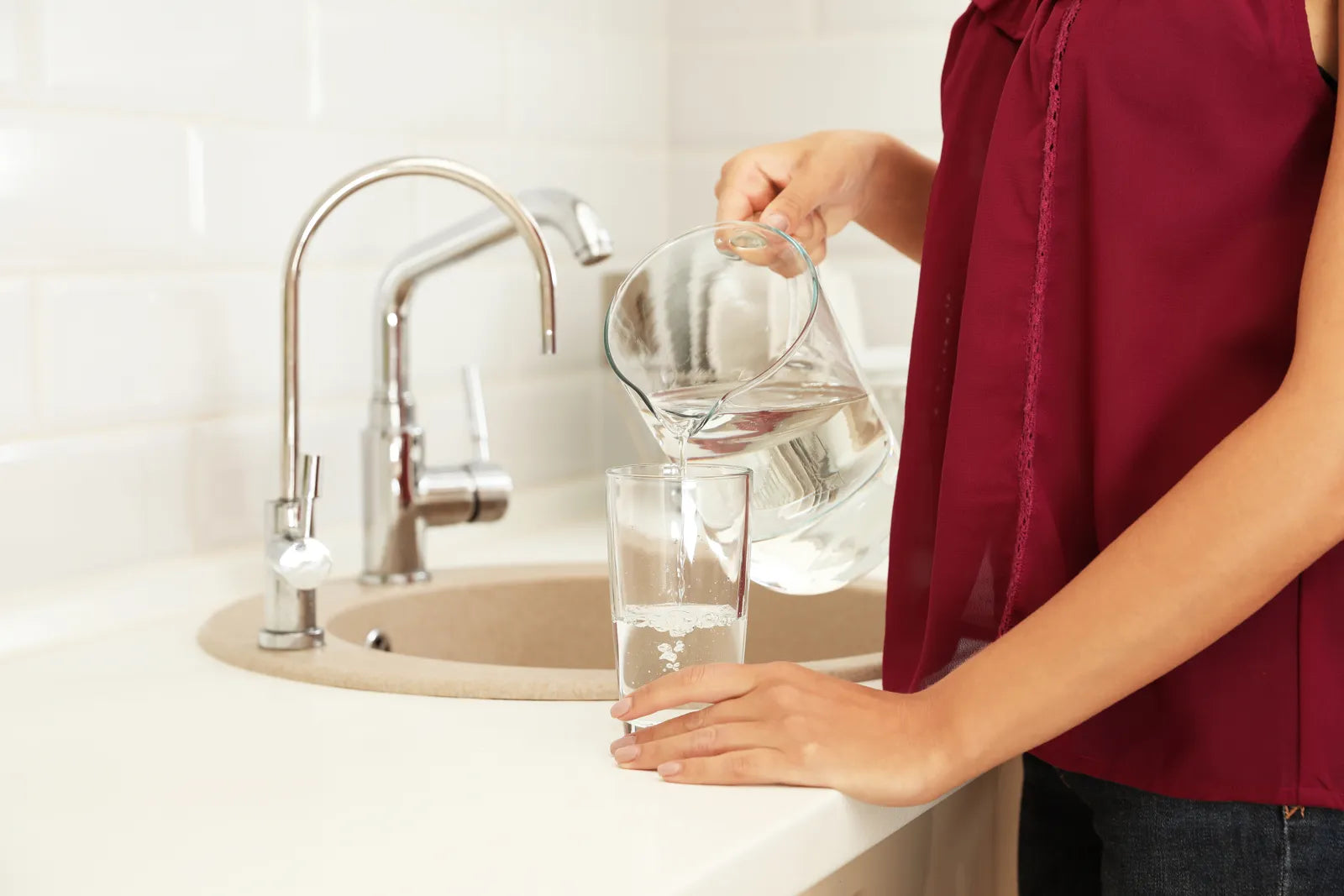 Person pouring clean water from a pitcher, showcasing the purified output of a top-tier water filter designed to eliminate PFAS.