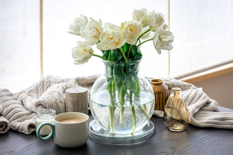 Cozy table setting with white tulips in a glass vase, showcasing the use of purified water to keep cut flowers fresh longer.