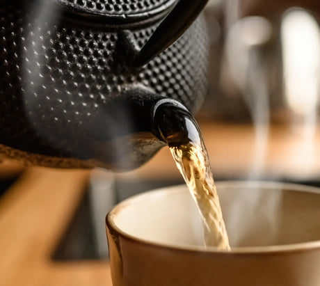Hot water pouring from a kettle into a teacup, using filtered water to enhance tea flavor and aroma.