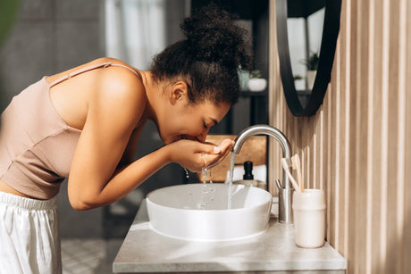 A woman washes her face with clean, filtered water at a bathroom sink.