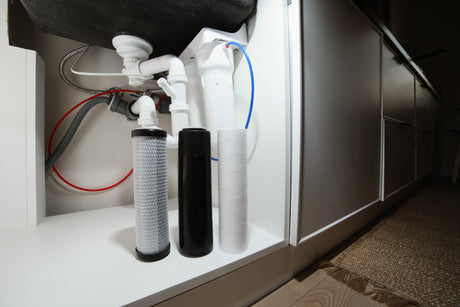 Reverse osmosis filter cartridges placed beneath a kitchen sink during a water filtration system maintenance process