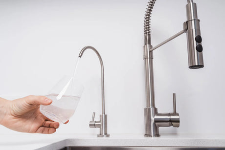 Glass being filled with water from a filtered tap, showing the temporary cloudy water effect after installing a new filter.