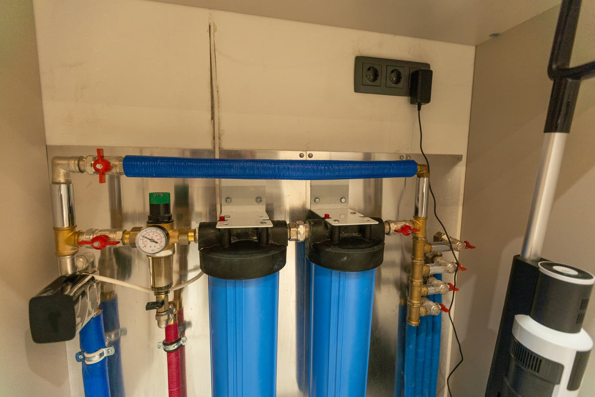 Water filtration system with large filter housings, pressure gauge, valves, and connected pipes