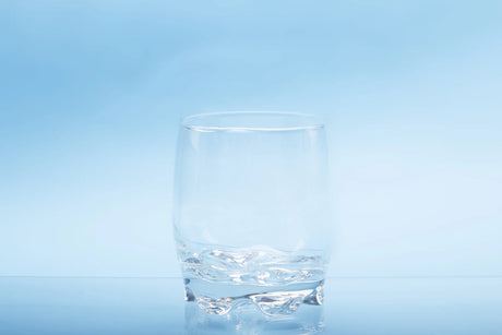 Clear glass of water on light blue background, showing nitrates in drinking water are invisible and undetectable to the eye.