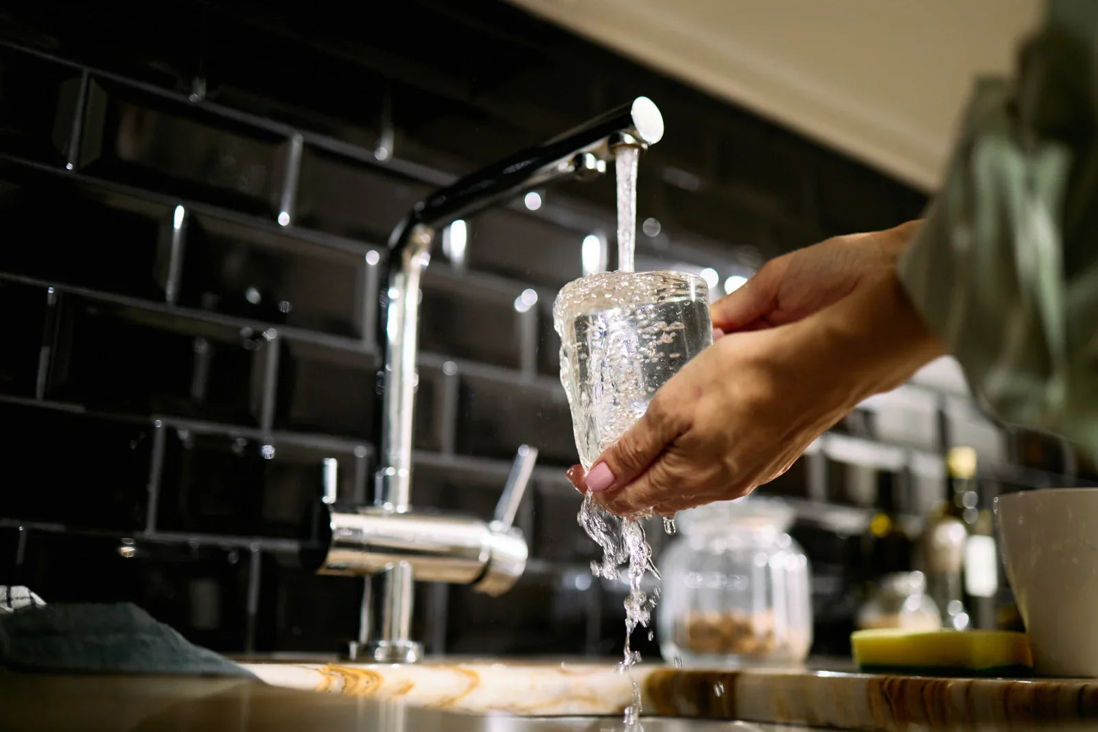 Pouring NSF-certified filtered water into a glass at a modern kitchen sink, ensuring safe drinking water.