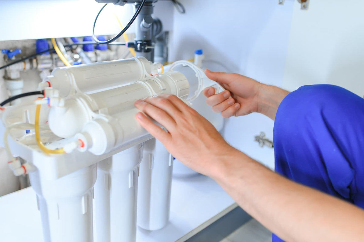 Technician opening an RO membrane housing during under-sink filtration system maintenance