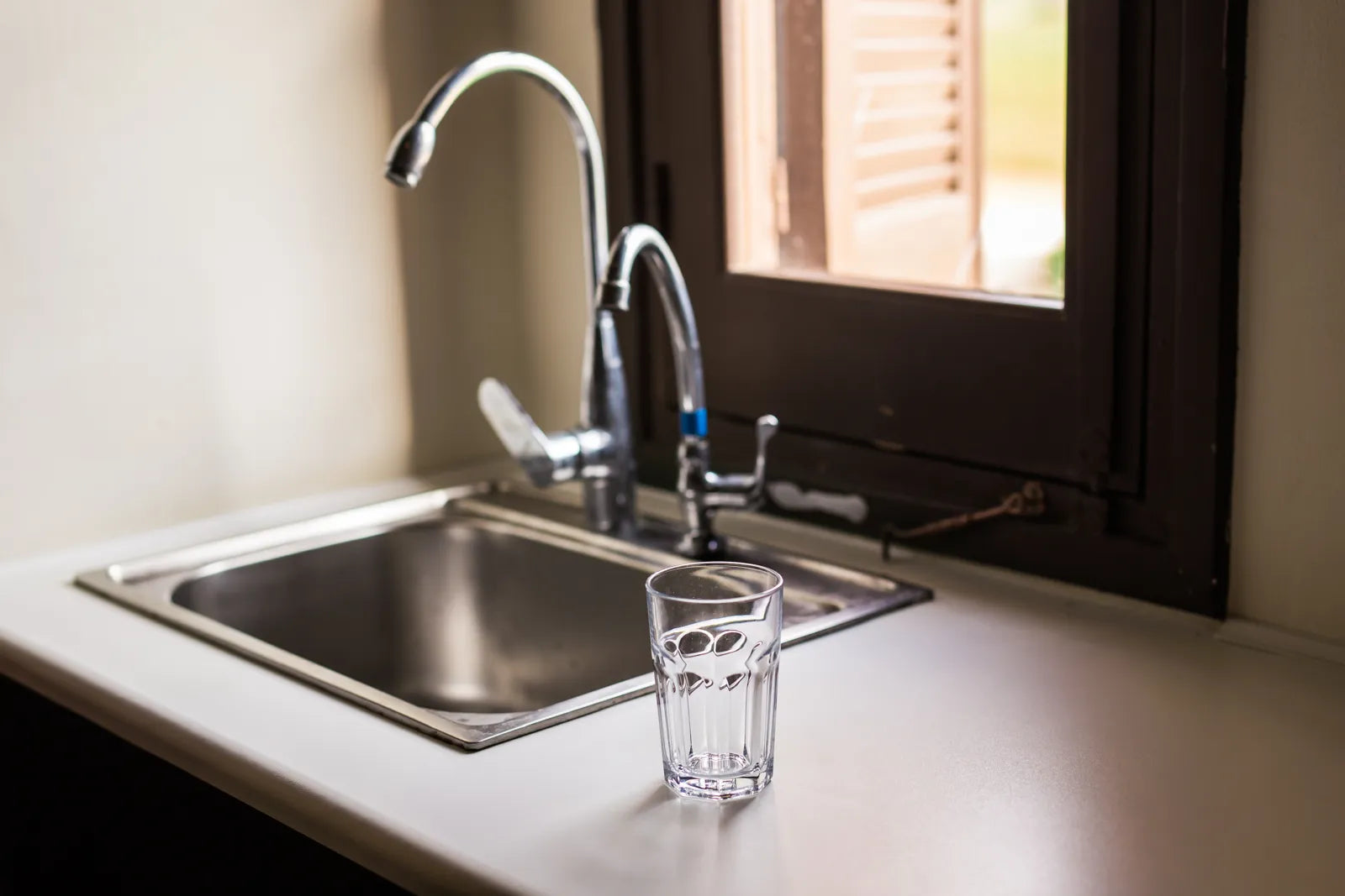 Kitchen sink with a glass of water, representing the clean water produced by RO systems and their associated yearly costs.