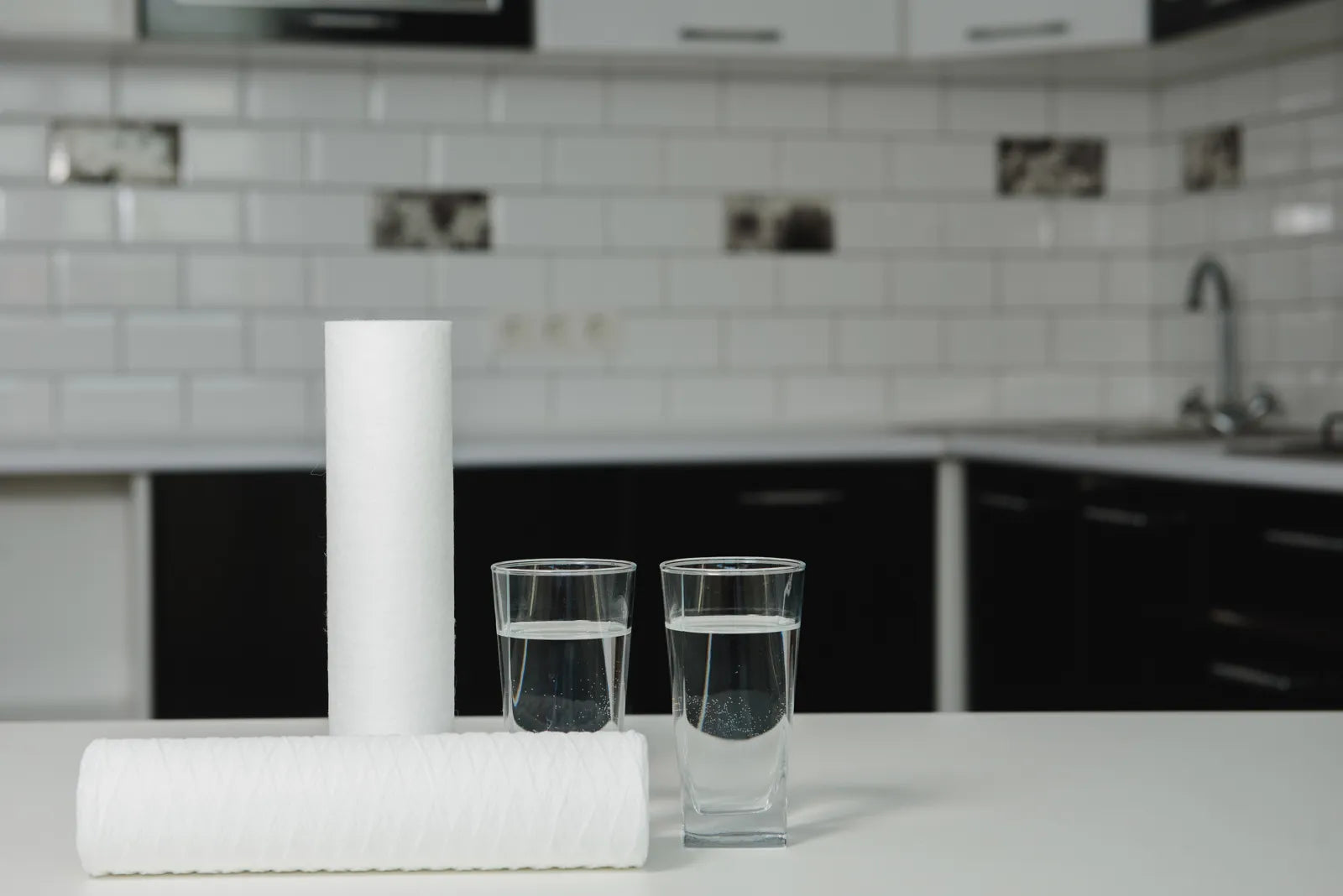 RO water filters alongside glasses of water, illustrating the core components of a reverse osmosis filtration setup.
