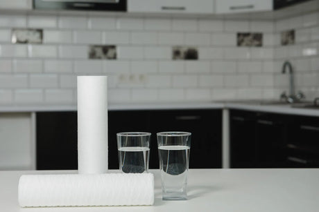 RO water filters alongside glasses of water, illustrating the core components of a reverse osmosis filtration setup.