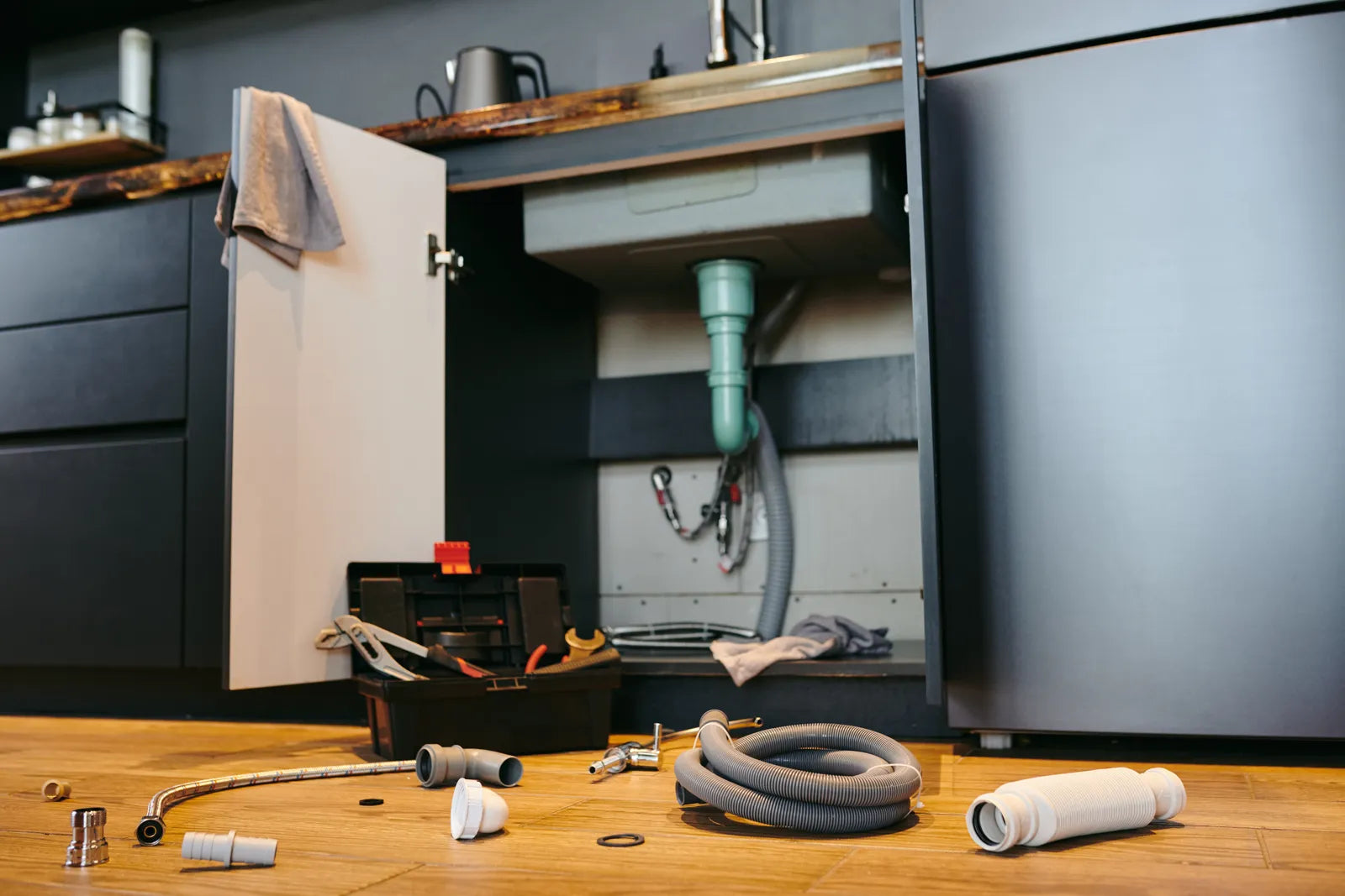 Plumbing parts lie ready for a reverse osmosis system installation under the sink.