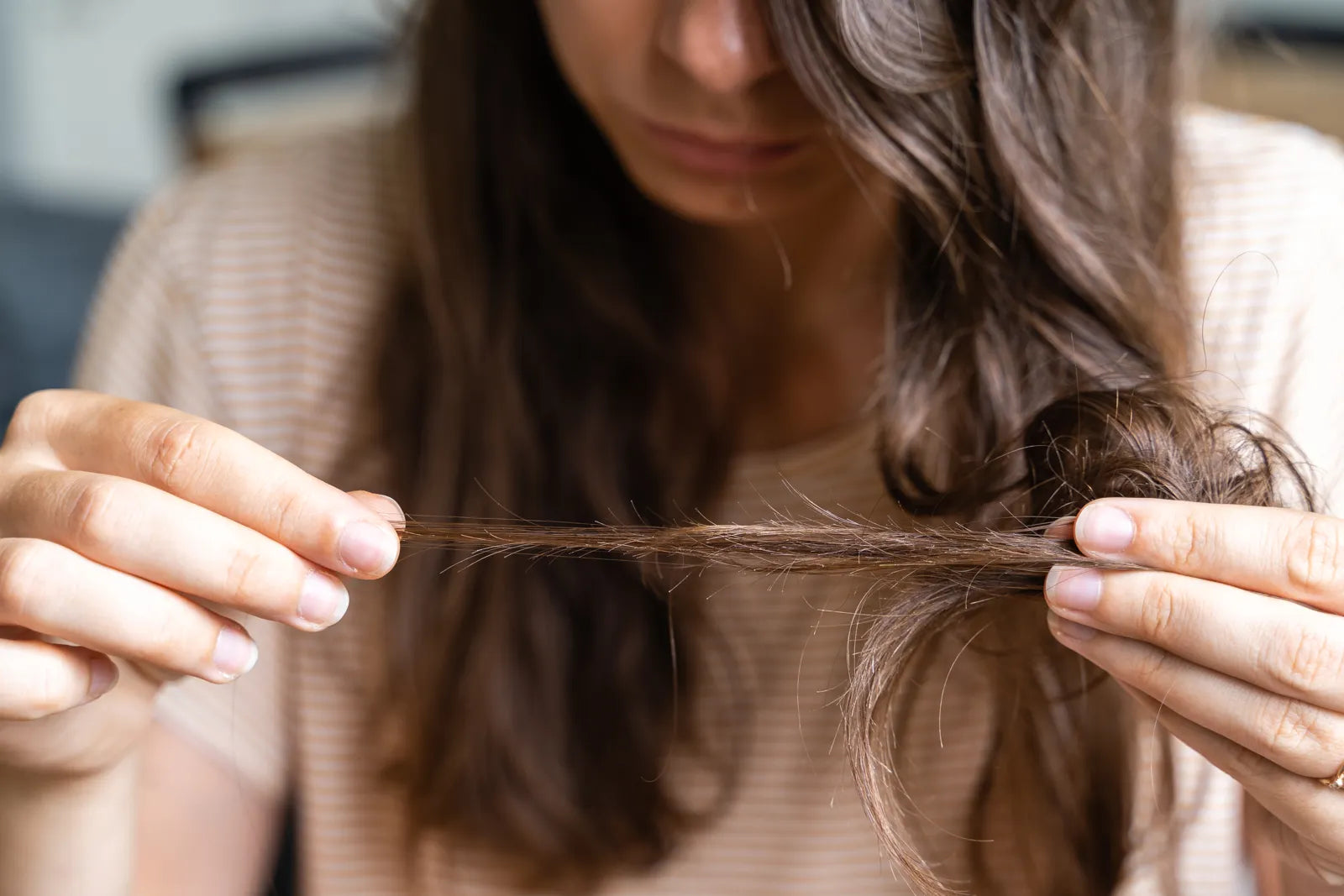 Woman checking damaged hair, showing effects of hard unfiltered water
