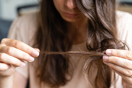 Woman checking damaged hair, showing effects of hard unfiltered water