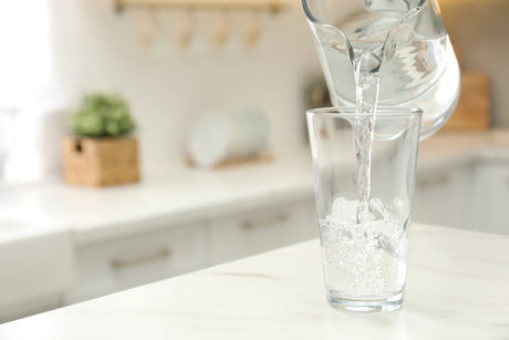 Water being poured into a glass, showing the final product of filtered water that may have altered TDS and hardness.