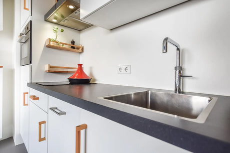 A modern apartment kitchen features space for an under sink water filter system.