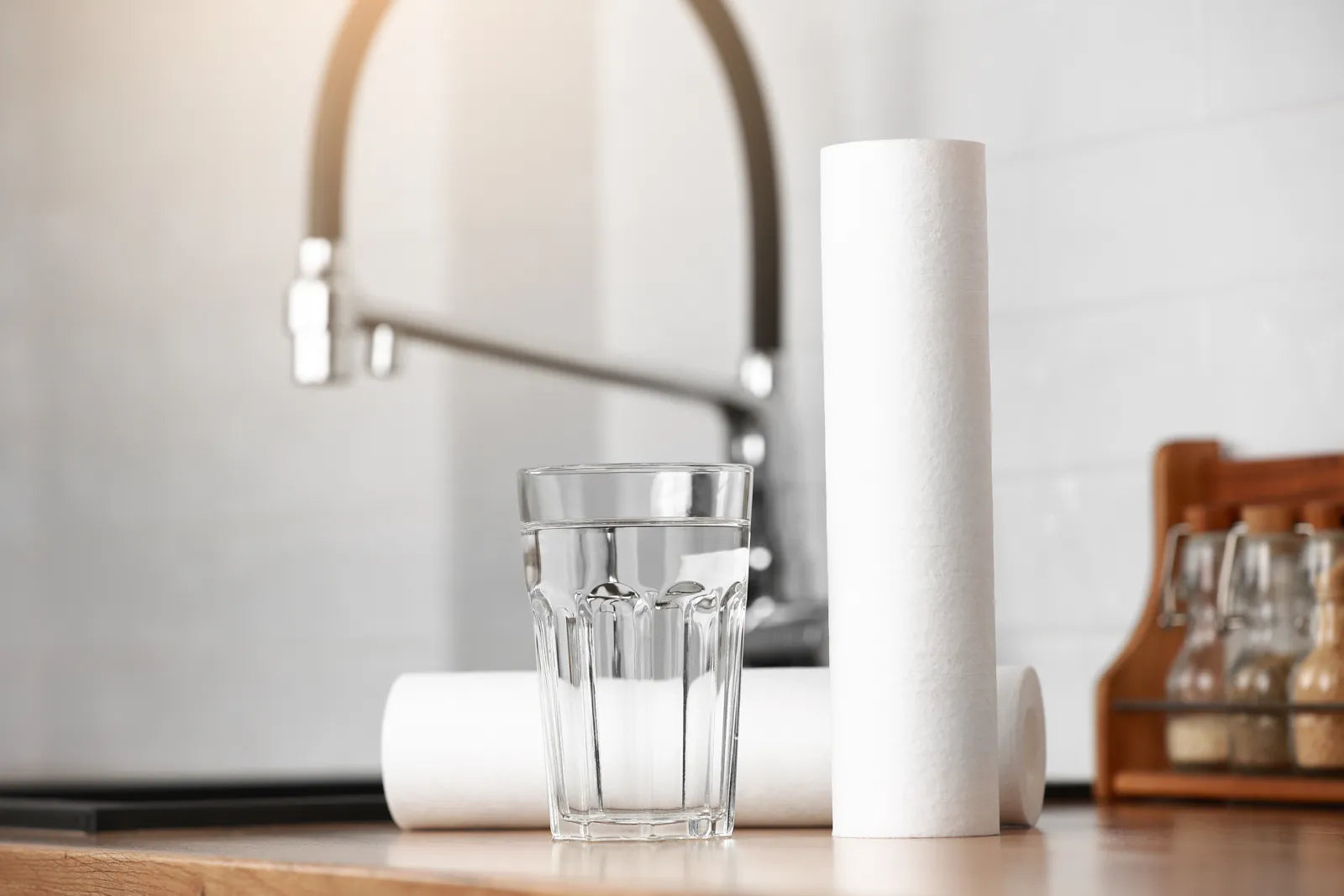 A glass of water beside a filter cartridge, showcasing how micron ratings determine water purification precision.