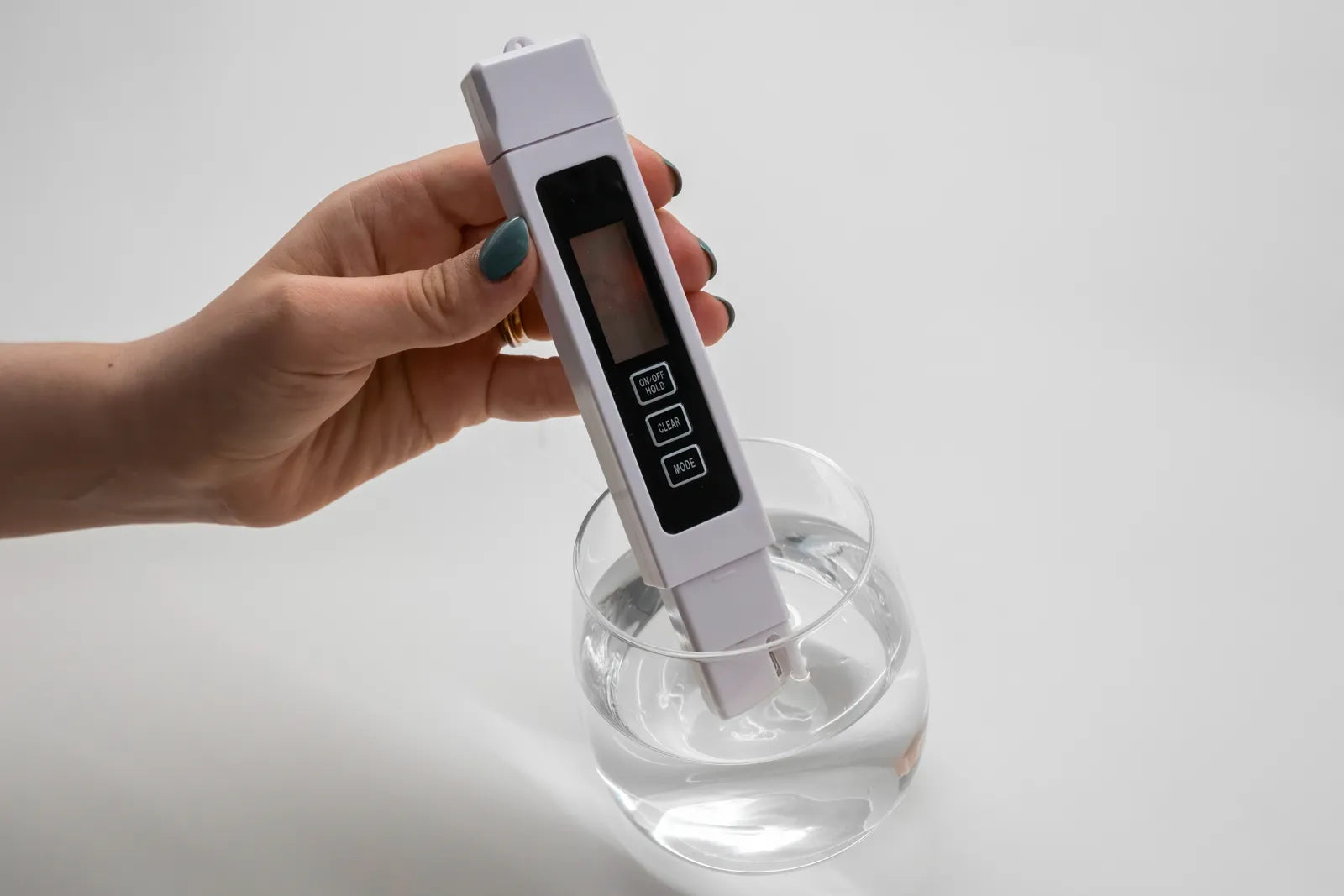A person uses a TDS meter to test the total dissolved solids in drinking water.