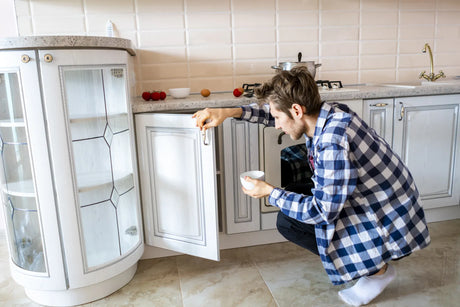 A homeowner inspects under the sink to find why their RO system is leaking.