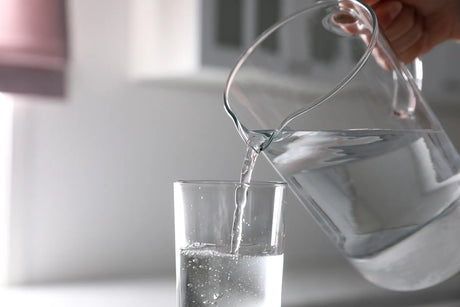 Pouring water from a pitcher highlights the risks of drinking distilled water long-term.